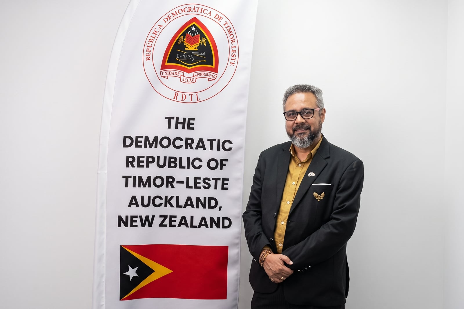 Dave Ananth, Honorary Consul of Timor-Leste, standing beside the Consulate banner in Auckland